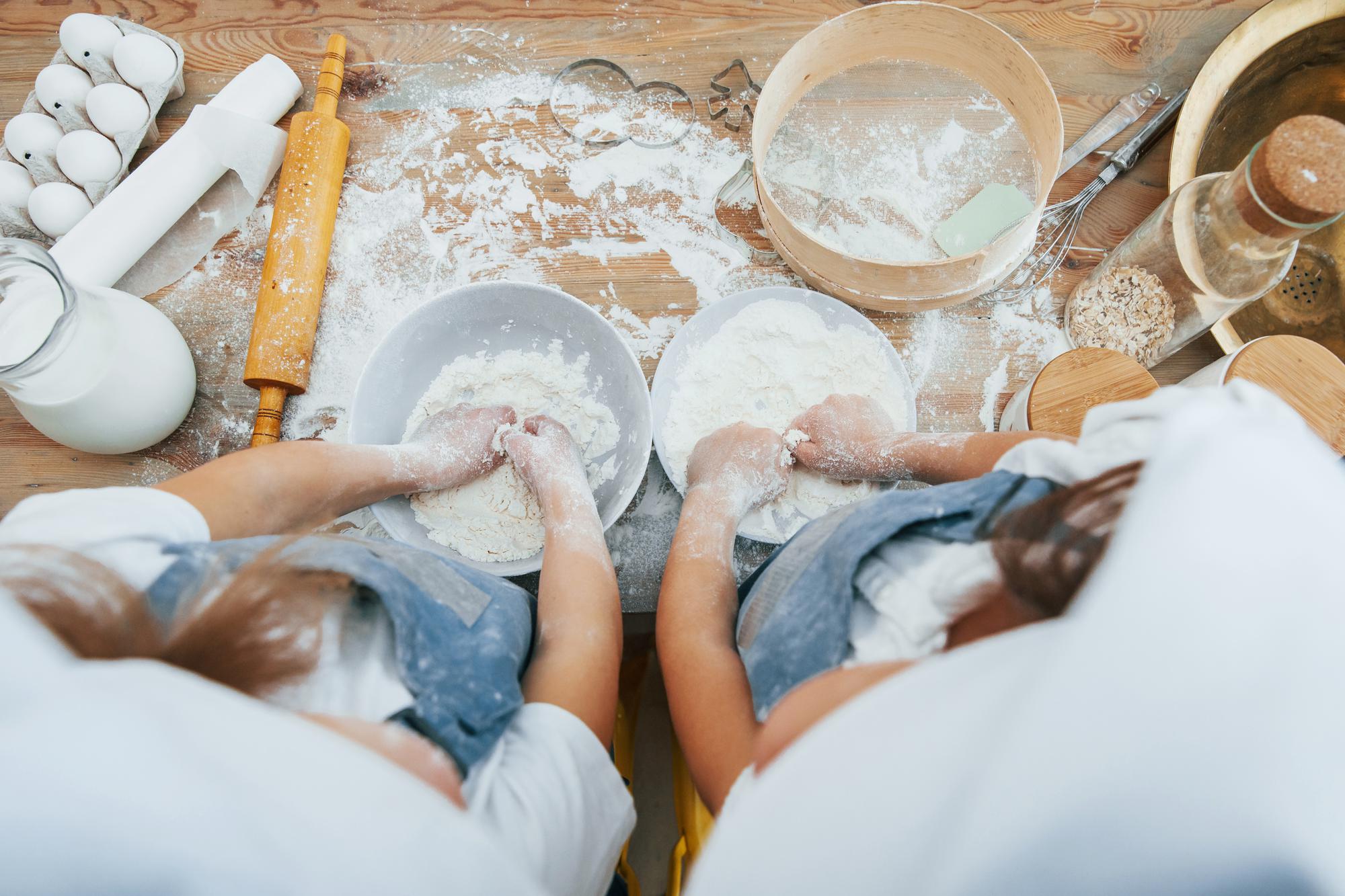 Students kneading dough around a wooden table